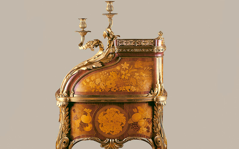 Secretária de cilindro, Jean-Henri Riesener. Paris, 1773. Estrutura em carvalho; marchetaria em sicómoro, amaranto, ébano, limoeiro e outras madeiras exóticas; bronze cinzelado e dourado; veludo. Museu Calouste Gulbenkian – Coleção do Fundador